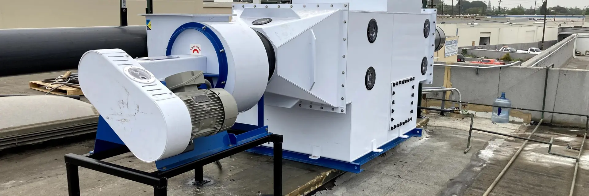 Rooftop fume scrubber with a white exhaust blower and PVC piping installed by 9EHS