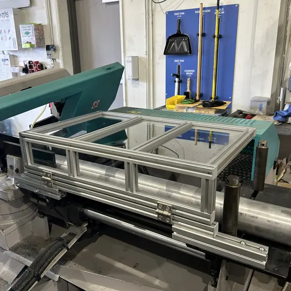 Horizontal band saw with a clear aluminum-frame guard over the cutting area