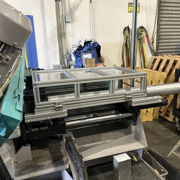 Aluminum-frame guard over the stock feed of a horizontal band saw