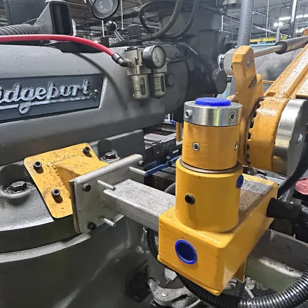 Close-up of the yellow guard arm mounting bracket on a Bridgeport mill