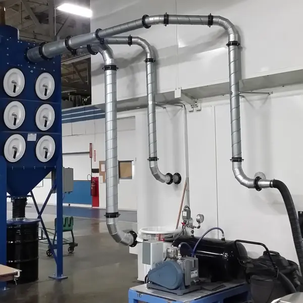 Cartridge dust collector with spiral ducting run down to a machine