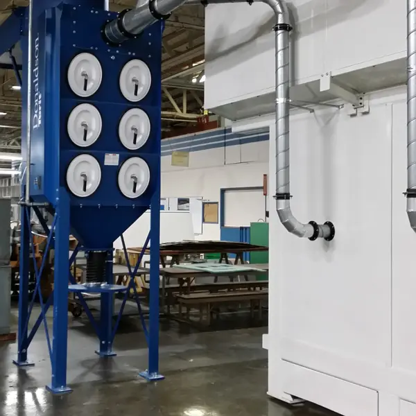 Blue cartridge dust collector with spiral ducting along a white wall