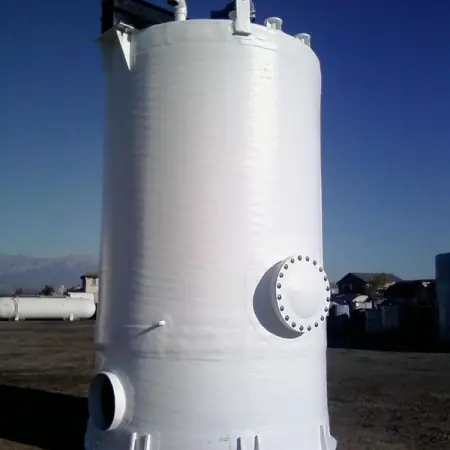 Vertical white FRP tank with a flanged manway, standing outdoors