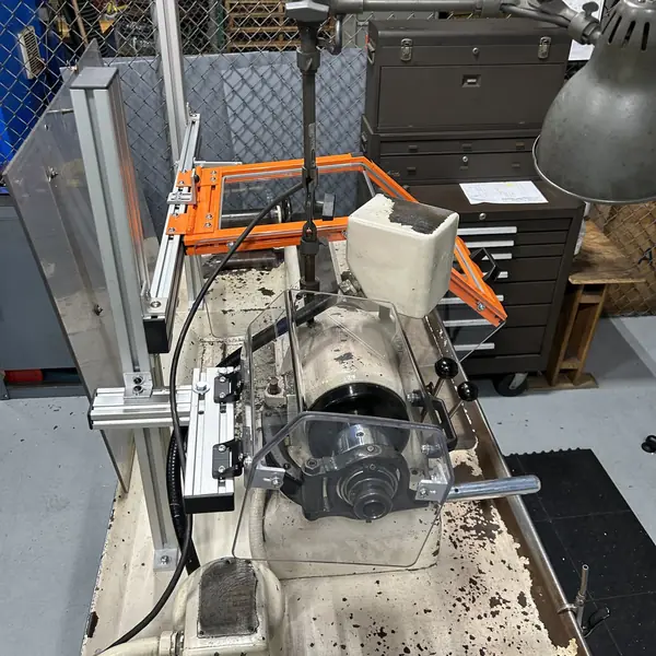 Hardinge lathe on a bench with an orange-frame guard on an aluminum mount