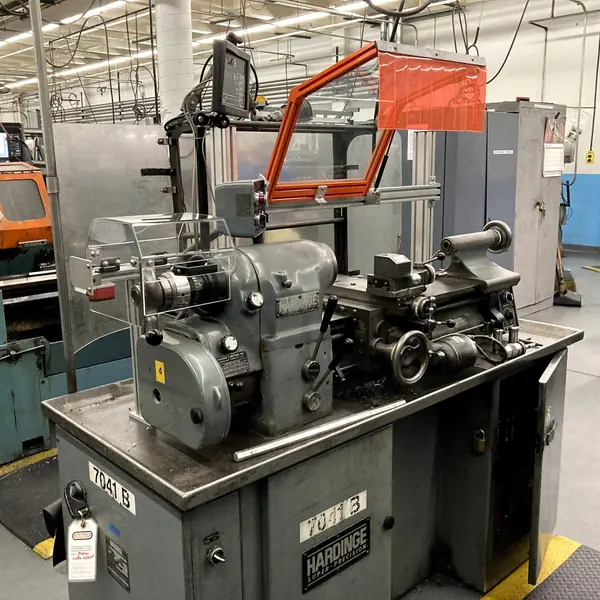 Hardinge lathe with an orange-frame chuck guard on a swing arm