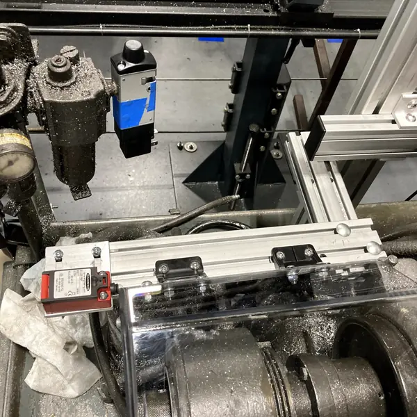 Close-up of an aluminum-frame guard with an interlock switch on a Hardinge lathe
