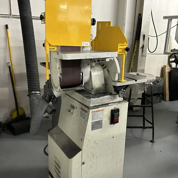 Jet belt grinder with yellow steel guards over the belt and wheel