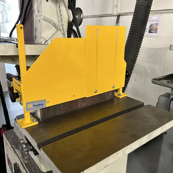 Close-up of a yellow steel guard on a Jet belt grinder table