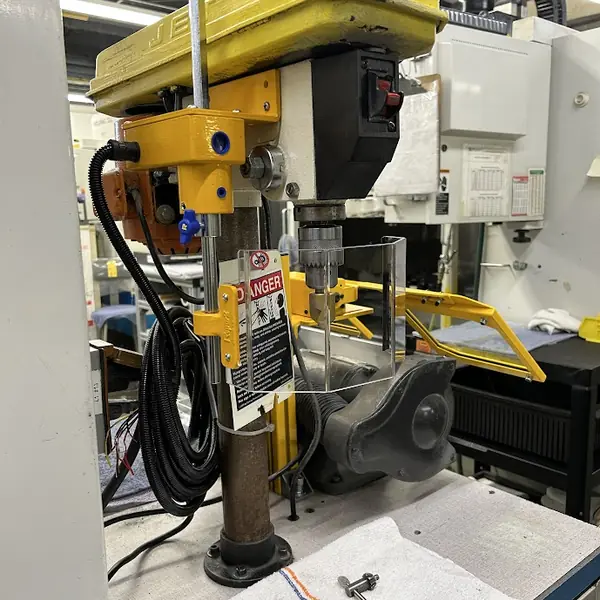 Jet drill press fitted with a yellow chuck guard and a danger warning tag