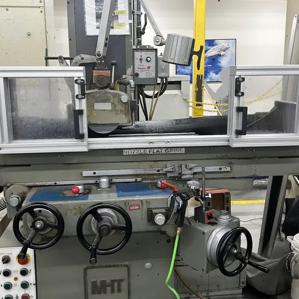 MHT surface grinder with an aluminum-frame guard along the table