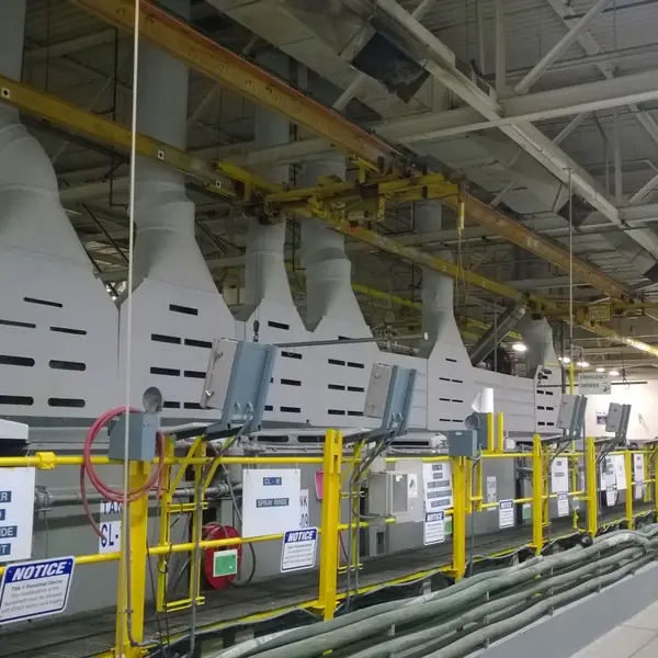 Plating line with white exhaust hoods, yellow rails and caution signs