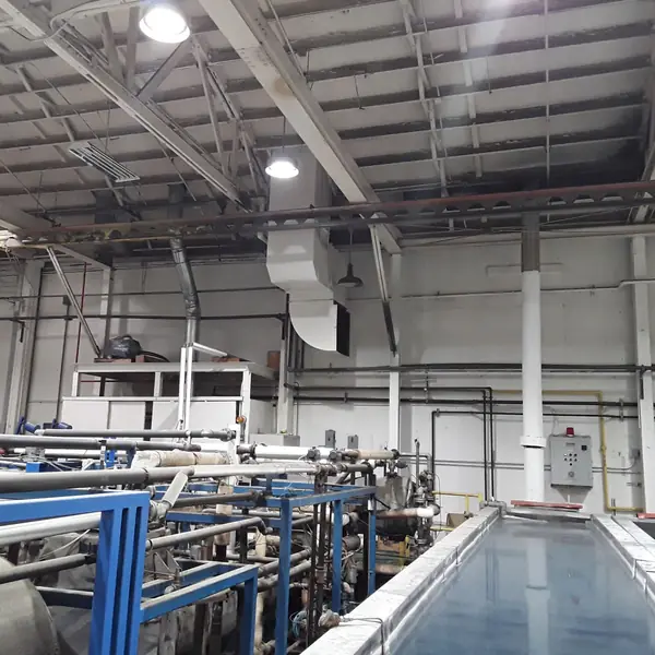 Open process tank on a blue steel frame inside a plating shop