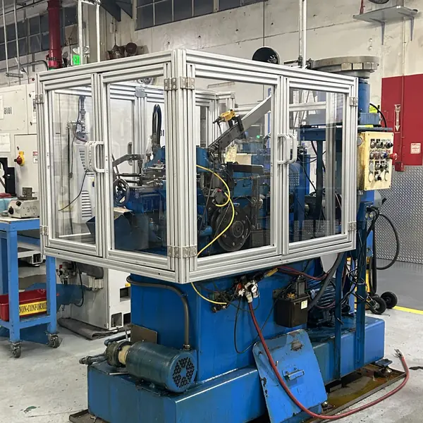 Aluminum-frame guard enclosure with clear panels and hinged doors around a small Rehart machine
