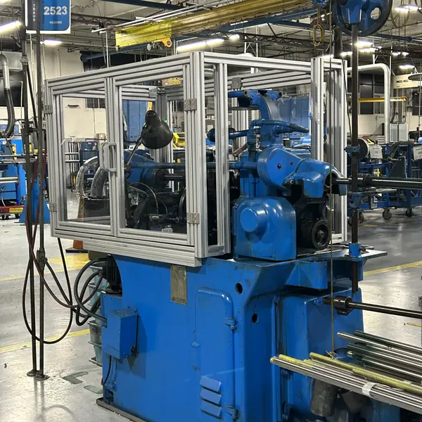 Side view of a Traub lathe inside a clear aluminum-frame guard enclosure
