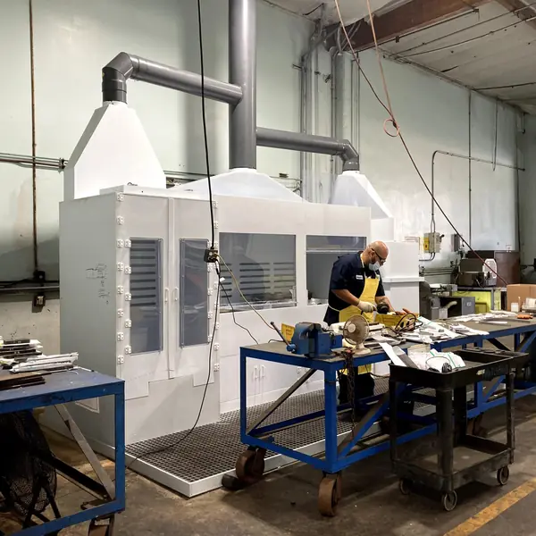 Ventilated white enclosure with an exhaust duct over a shop workstation