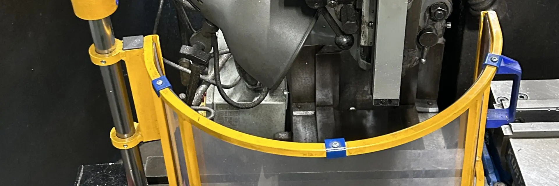 Yellow articulating arm and curved clear spindle shield guarding a Bridgeport milling machine